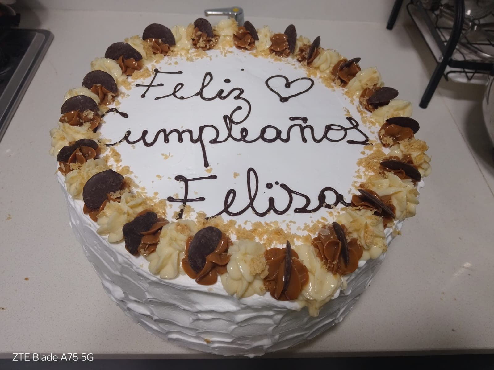 Torta redonda con crema y bombones y el mensaje "Feliz Cumpleaños Felisa" escrito a mano